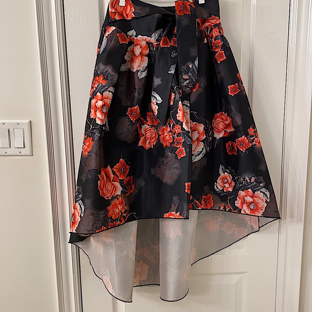 Black with floral skirt. Shorter front and comes longer in back